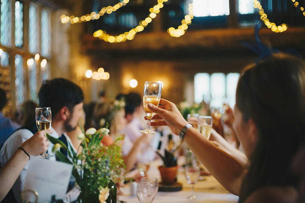 Image of people sitting at a formal table raising champagne glasses in a toast