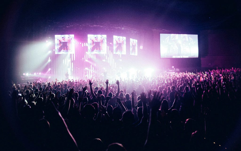 Massive crowd facing a large brightly-lit stage.