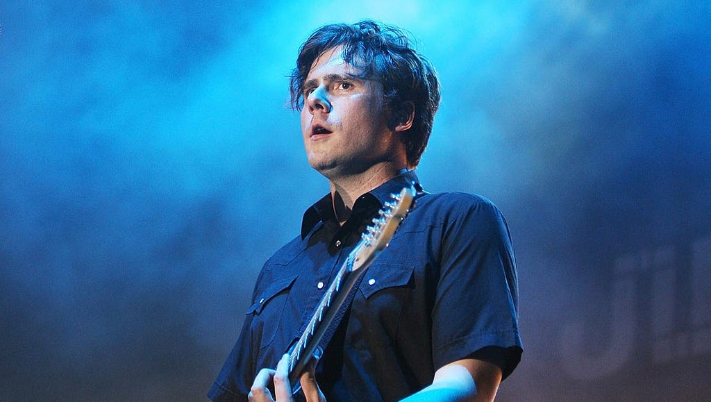 Jim Adkins of the band Jimmy Eat World plays a guitar on a concert stage