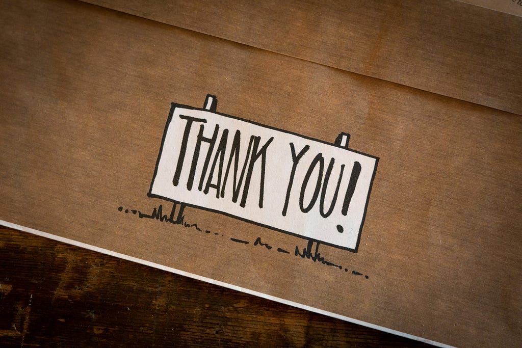 This image depicts cardboard with the words “Thank you!” written on it.
