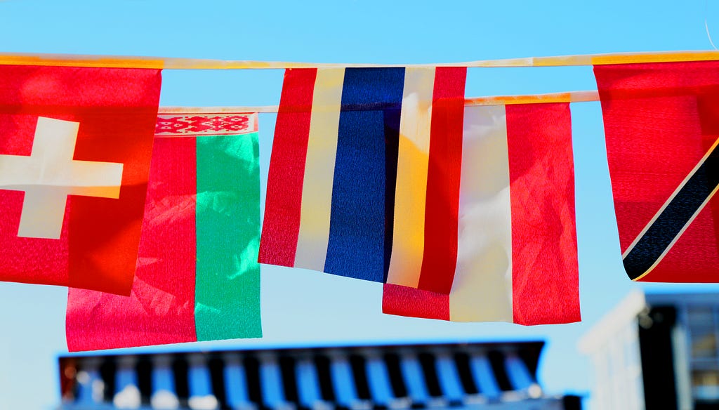 A series of flags hang together above a blue roof, a display of international solidarity