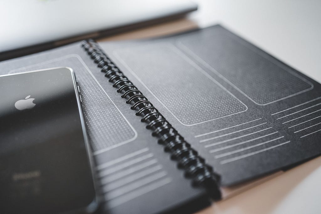 A black iPhone on top of a prototyping notebook