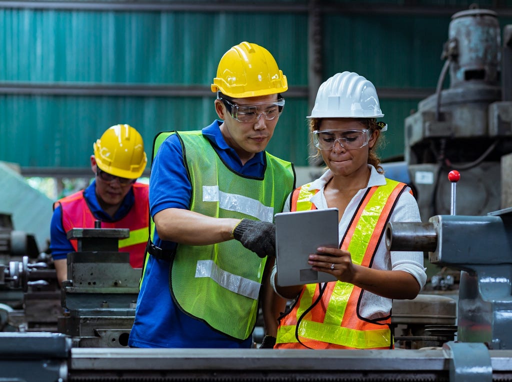 Two people review machine logs in a factory. Photo by Yozayo/Getty Images