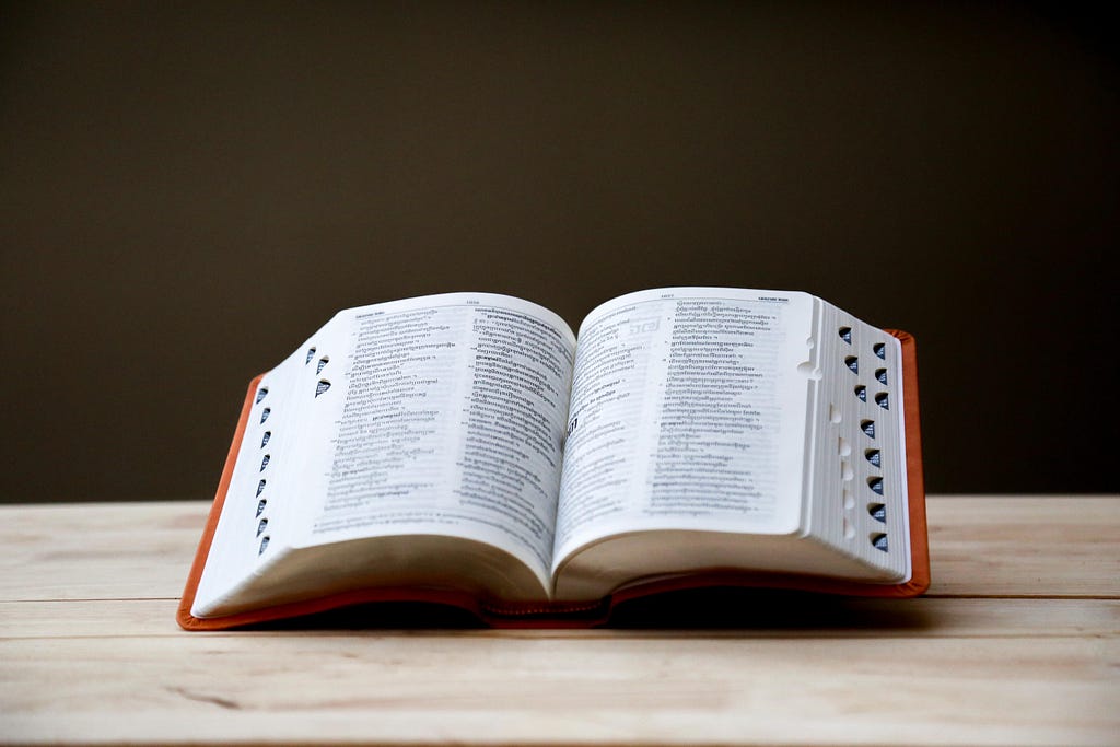 An open dictionary sits on a wooden table