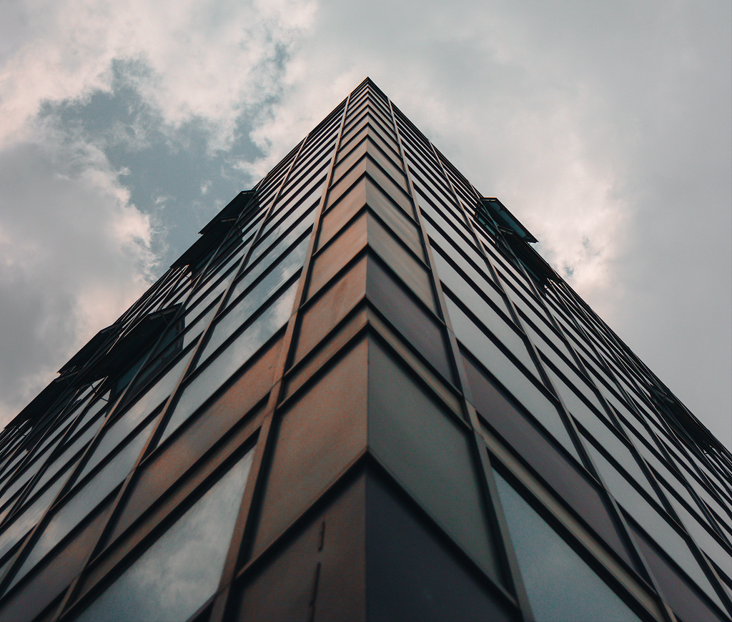 Low-angle photograph of a tall building under clouds