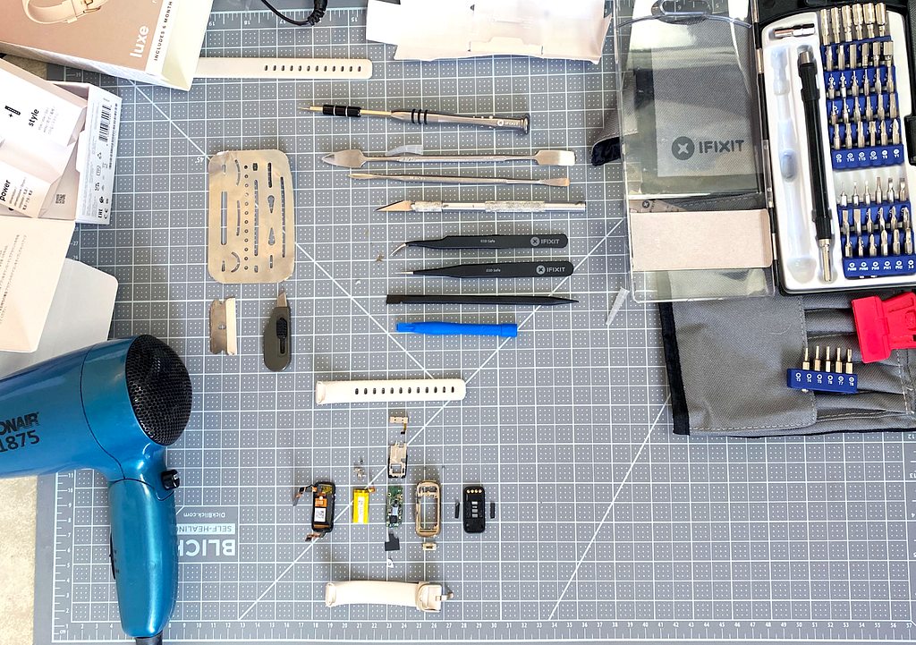 Image of workspace with various tools and fitbit assembly laid out