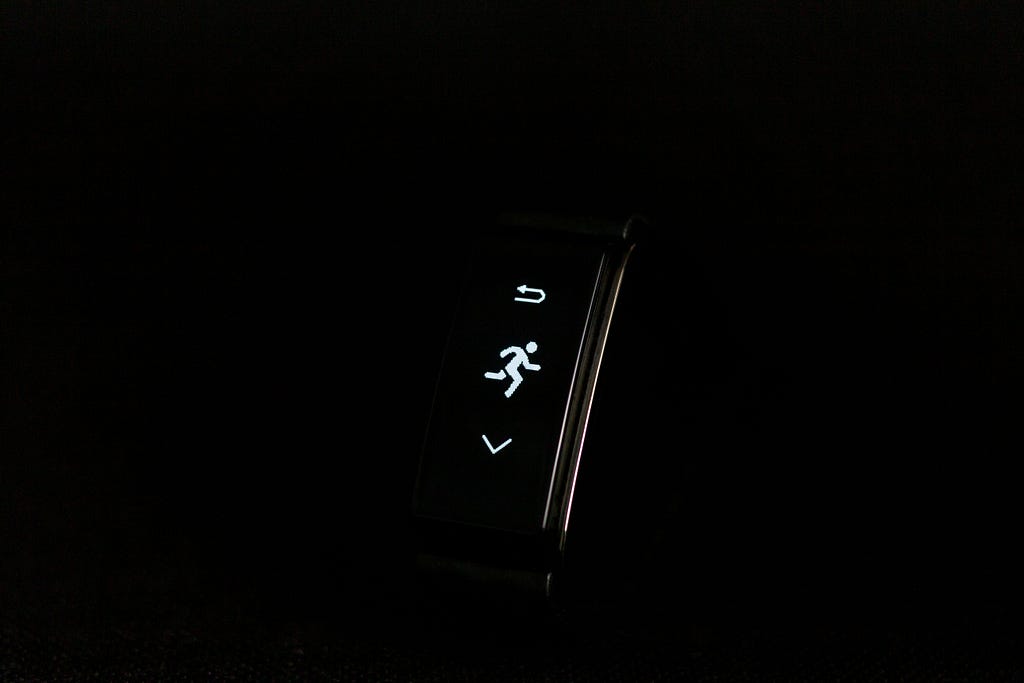 A glowing face of a wearable activity tracker denoting a running figure