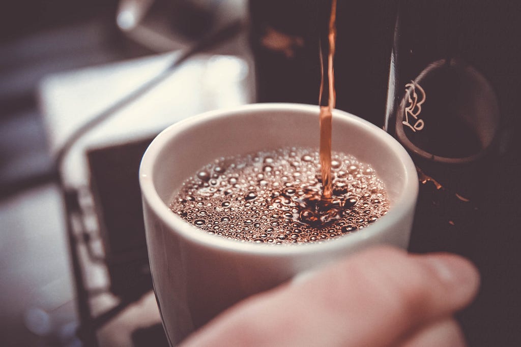 Xícara de café sendo enchida pela máquina de café