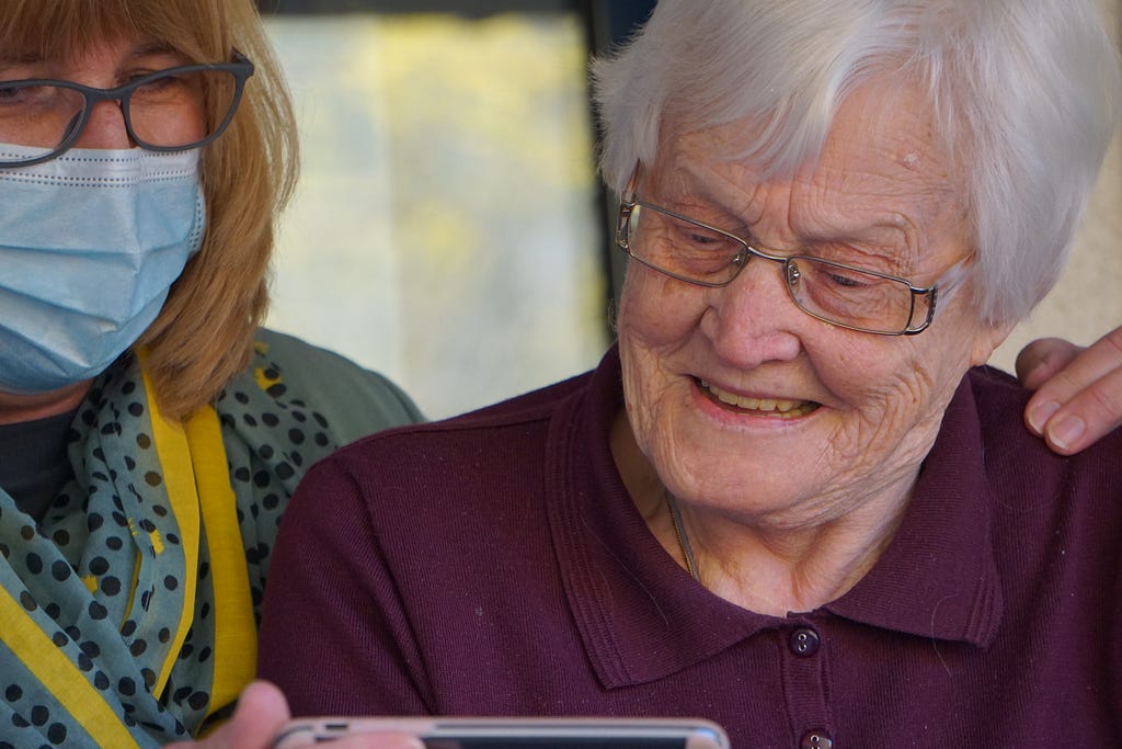 Older and younger woman holding a smartphone and looking at the screen