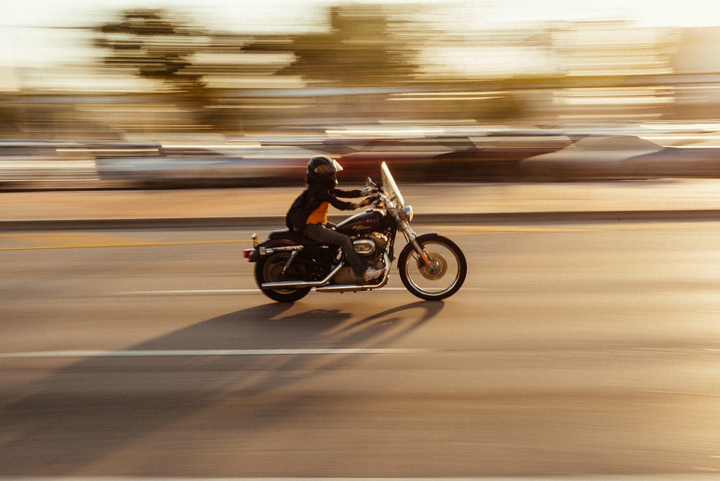 A person on a motorcycle with background blurred to show speed.