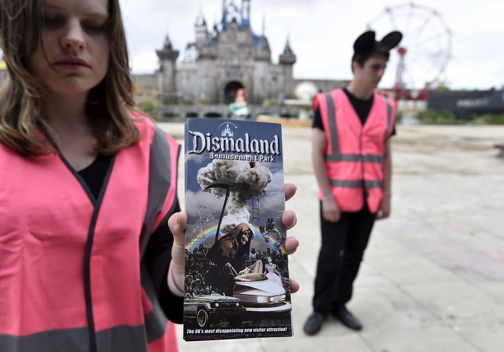 A performer holds a brochure for 'Dismaland', a theme park-styled art installation by British artist Banksy, at Weston-Super-Mare in southwest England