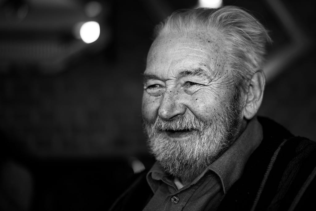 an old man smiling in a black and white picture