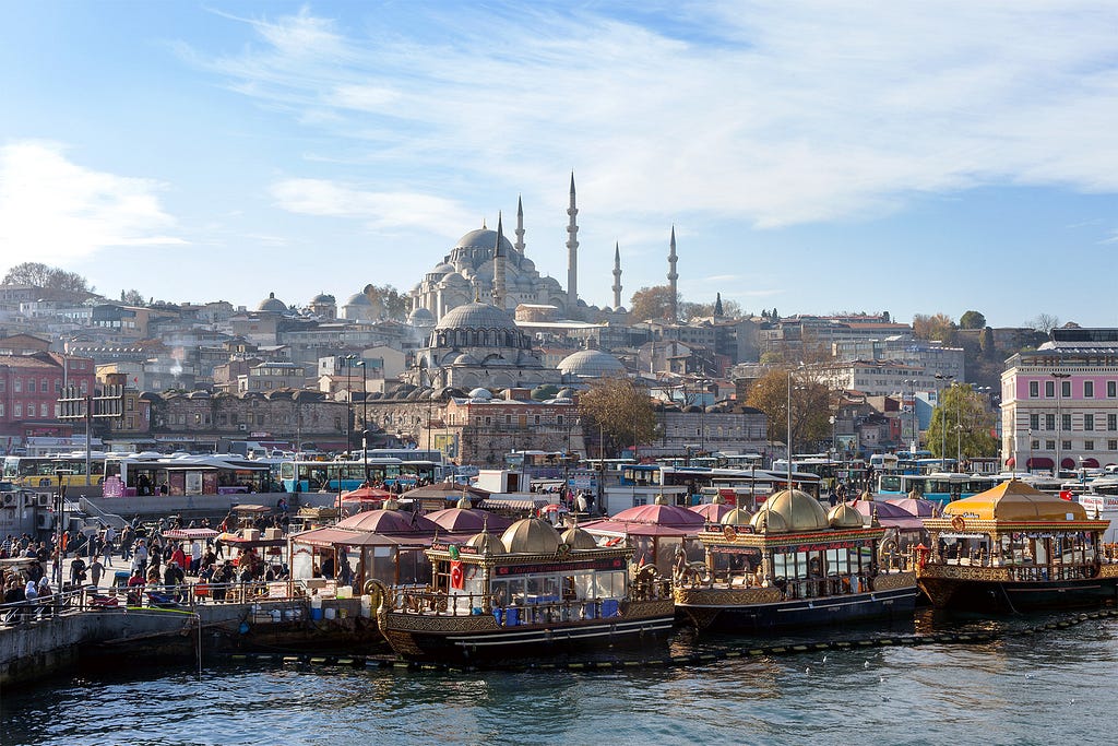 busy ferry terminal filled with colorful boats and a mosque looming in the background