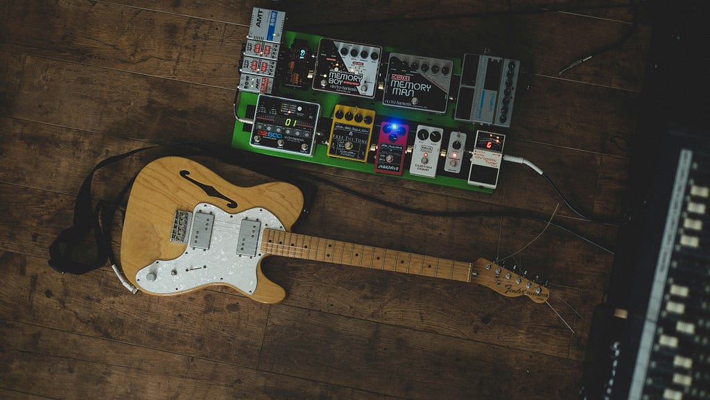 A guitar and effects pedalboard on the ground