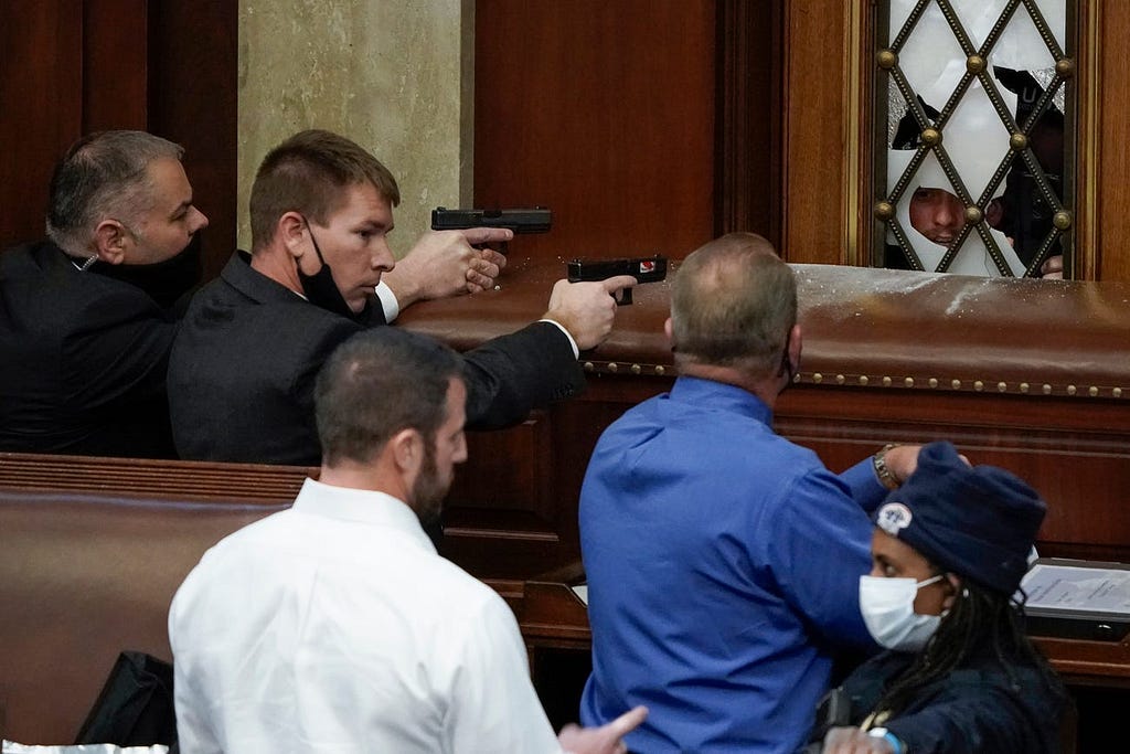 U.S. Capitol Police with guns drawn watch as protesters try to break into the House Chamber at the U.S. Capitol.