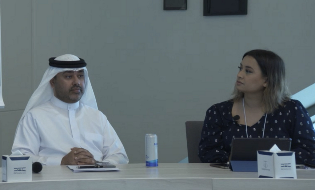 A man and a woman sit at a desk.