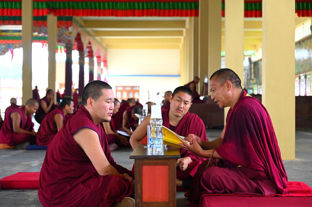 A monk giving the examination on a text he has memorized. The examiner (right) chooses passages at random and the student (left) has to finish the passage from memory.