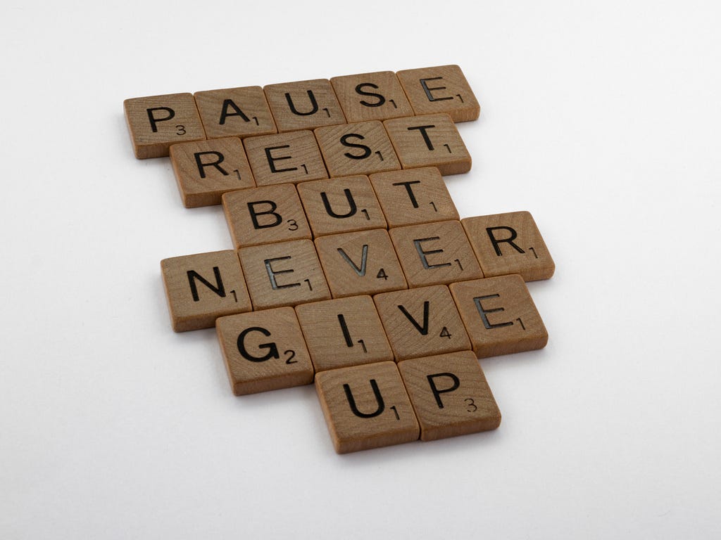 Photo of Scrabble letters making words of “Pause rest but never give up”