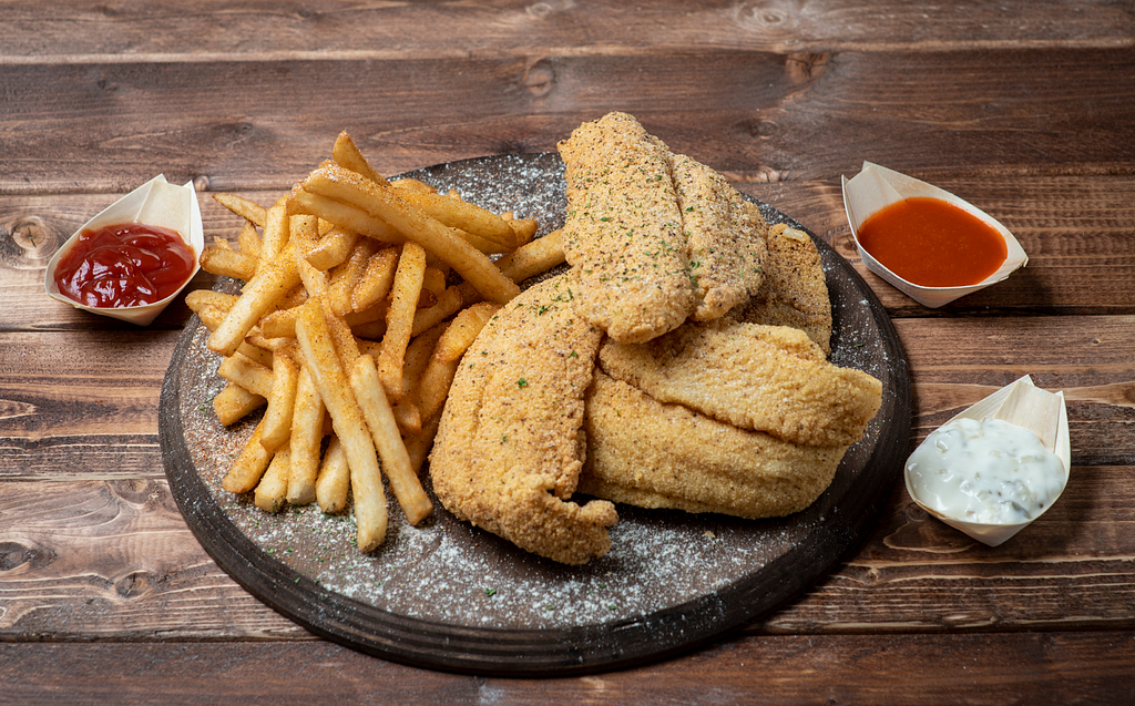 Platter with Fried Catfish and french fries and sides of tartar sauce, ketchup, and hot sauce.