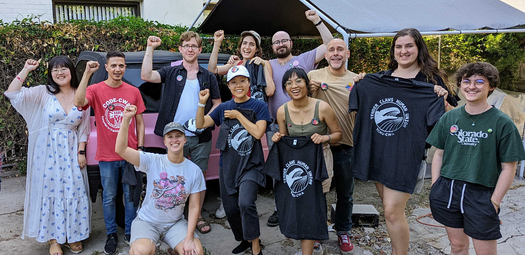 A Stripper Strike organizer, unionizing Tender Claws workers, and allies pose for a group photo, showing off recently constructed union buttons and t-shirts