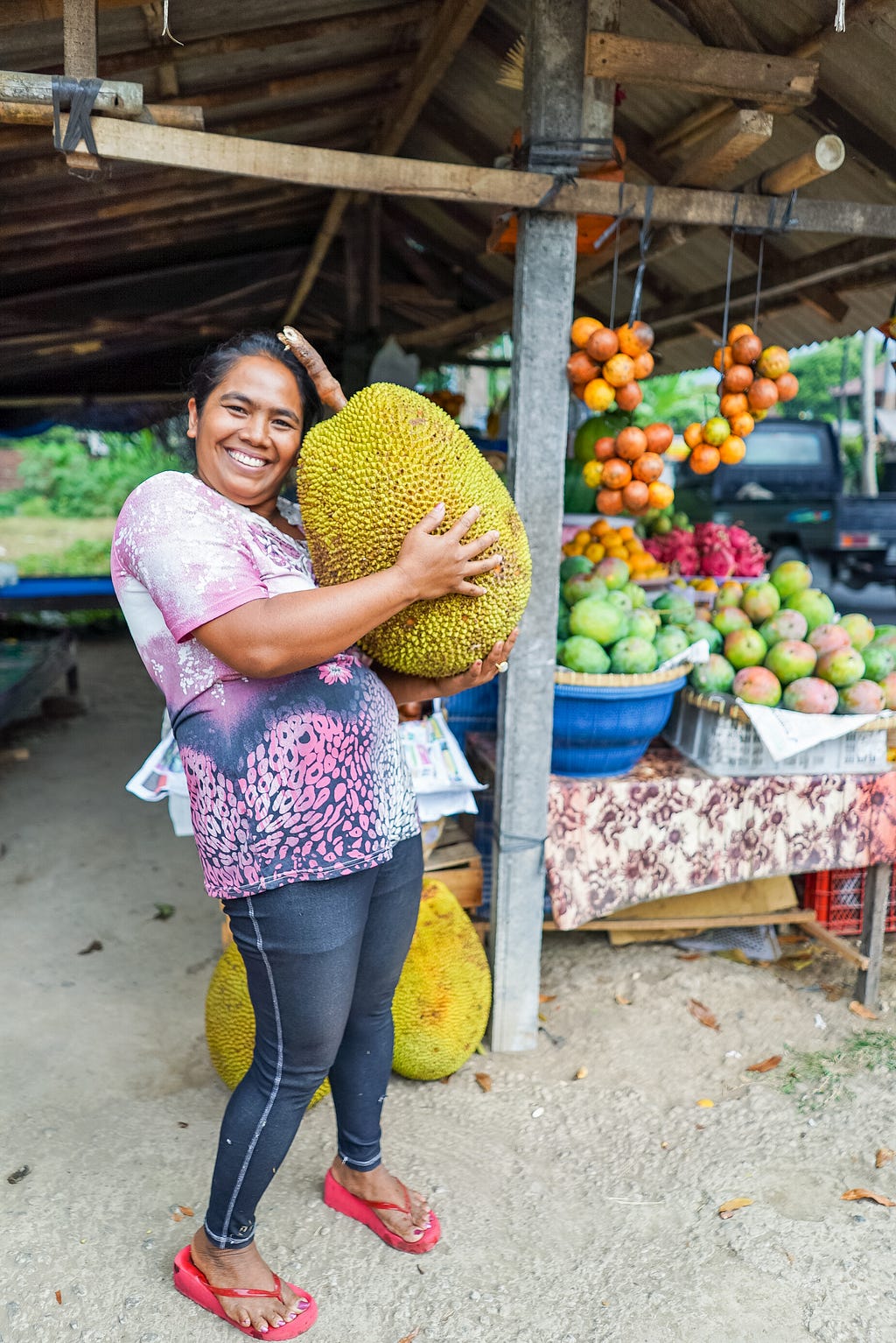woman holding large jackfruit in local market
