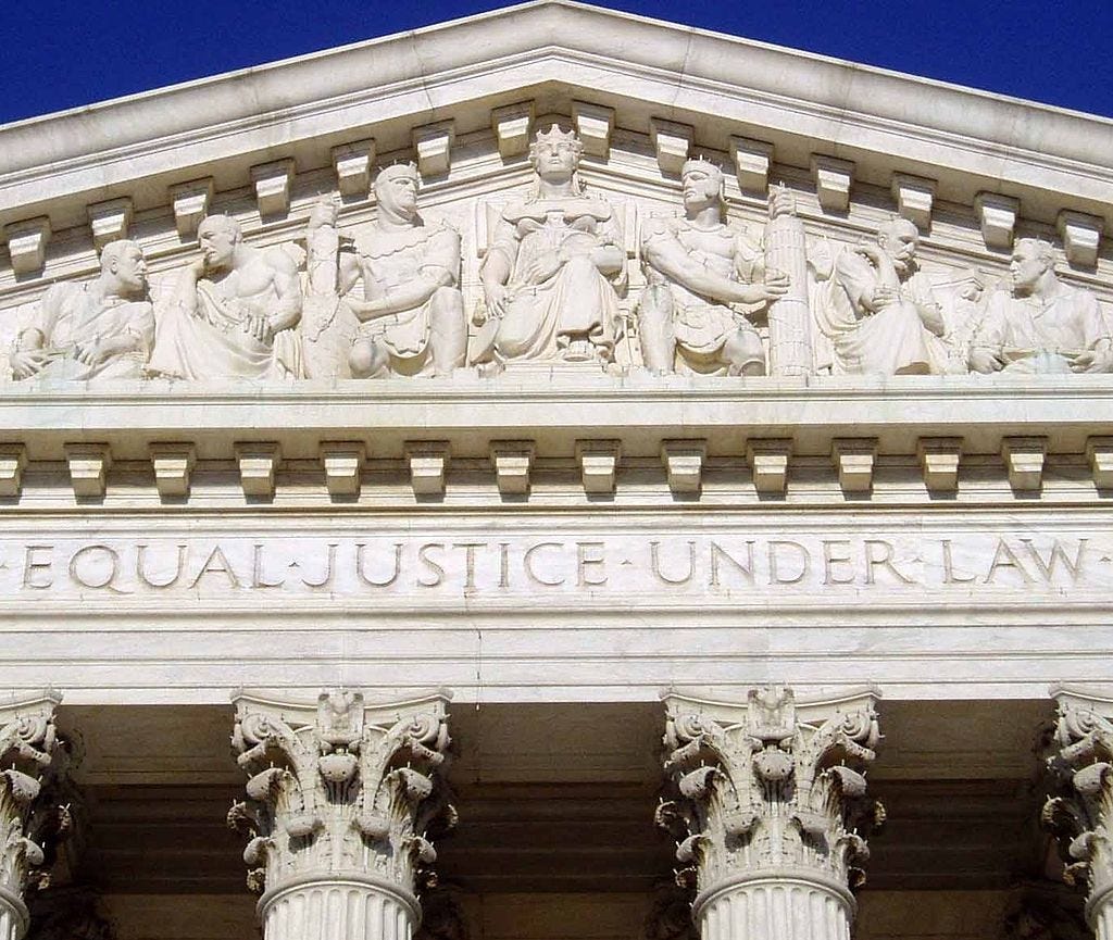Detail of the carvings on the West pediment of the U.S. Supreme Court Building, with figures up top, and the words “Equal Justice Under Law” below.