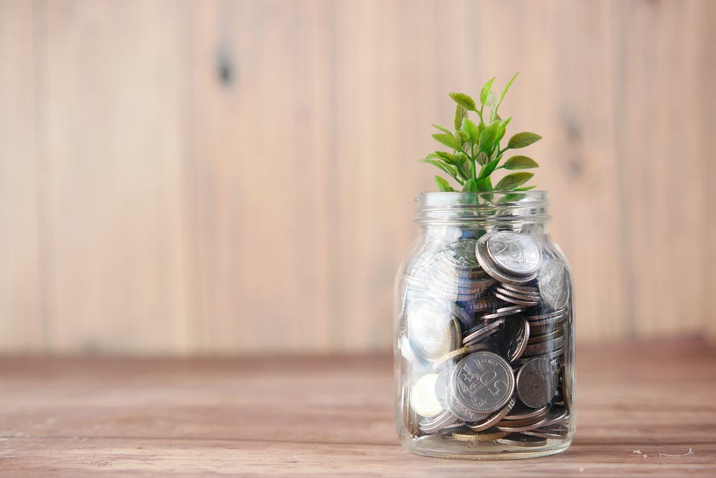 A jar full of coins and a plant sprouting on top