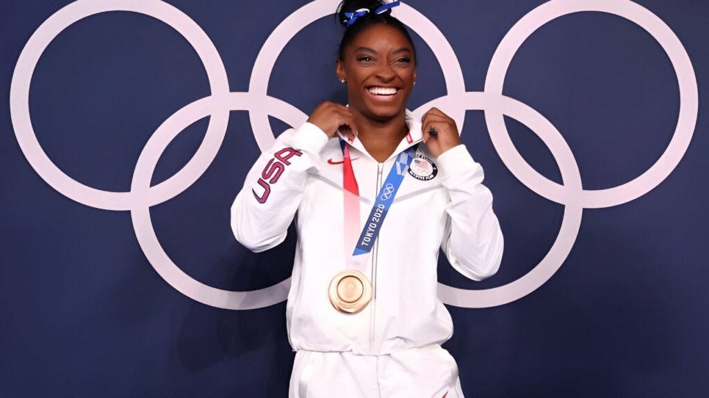 Simone Biles of Team USA poses with the bronze award after the Women's Balance Beam Final on August 3, 2021, at the Ariake Gymnastics Center in Tokyo, Japan. This happened on the eleventh day of the Tokyo 2020 Olympic Games. (Image from Getty Images by Laurence Griffiths)1)