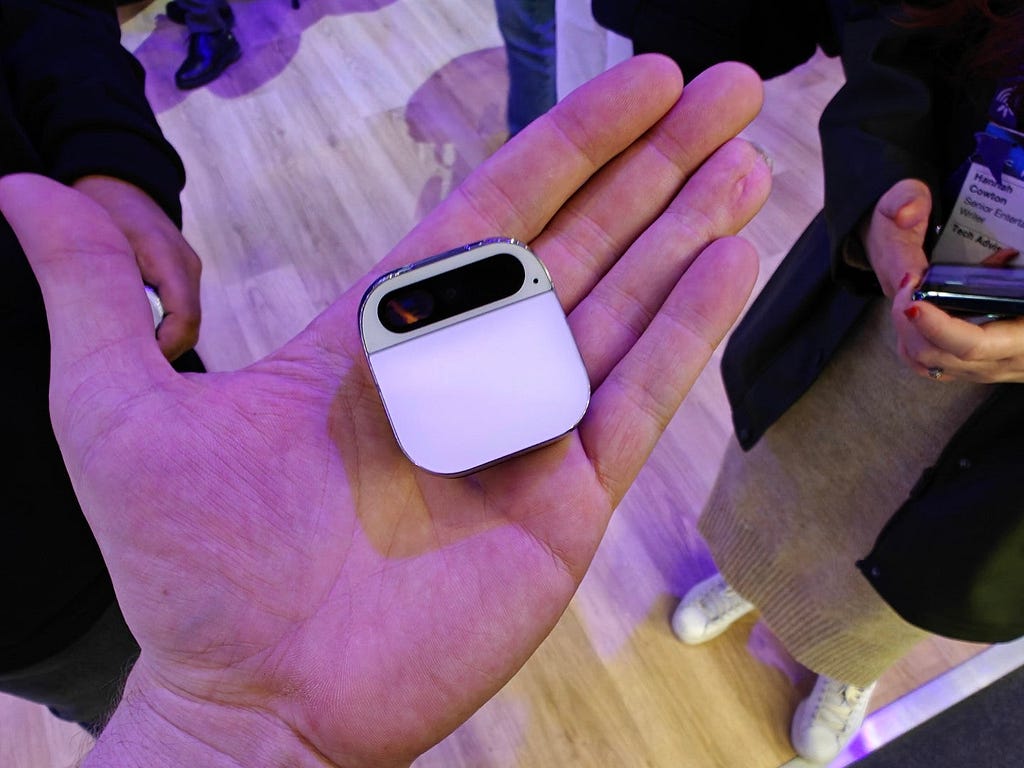 A man holds the Ai Pin by Humane in his hand at a tech event.