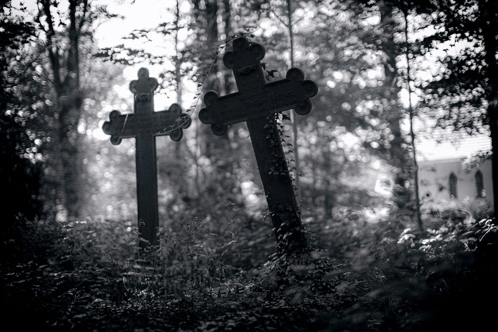 Two cross grave markers in the middle of a forest.