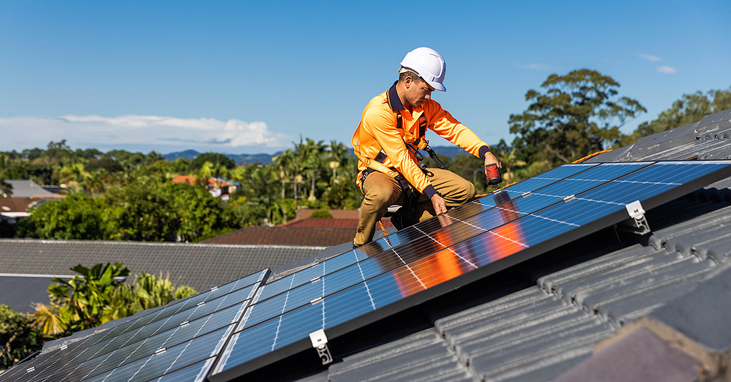 a solar panel installer works on the roof of a house