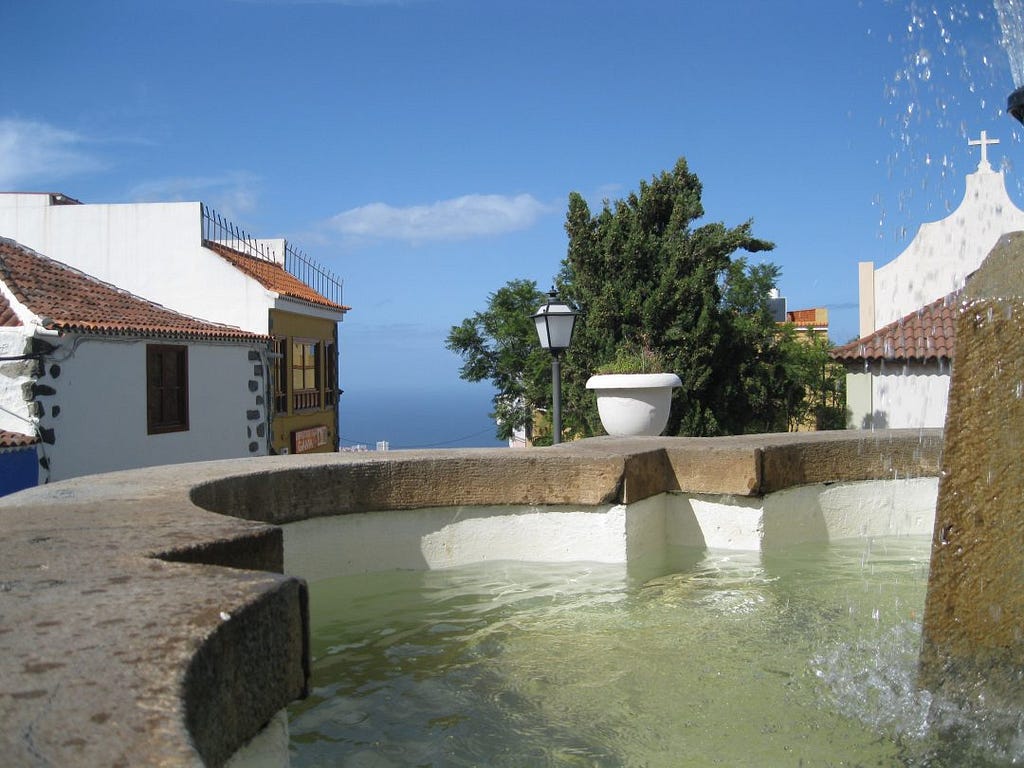 A fountain with typical Canary islands houses behind