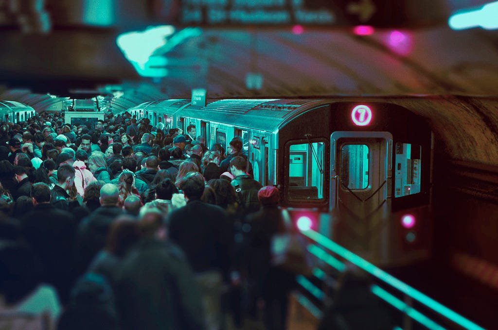 “Leading the Mob”. A crowded subway platform filled-shoulder-shoulder between parked trains on both sides.