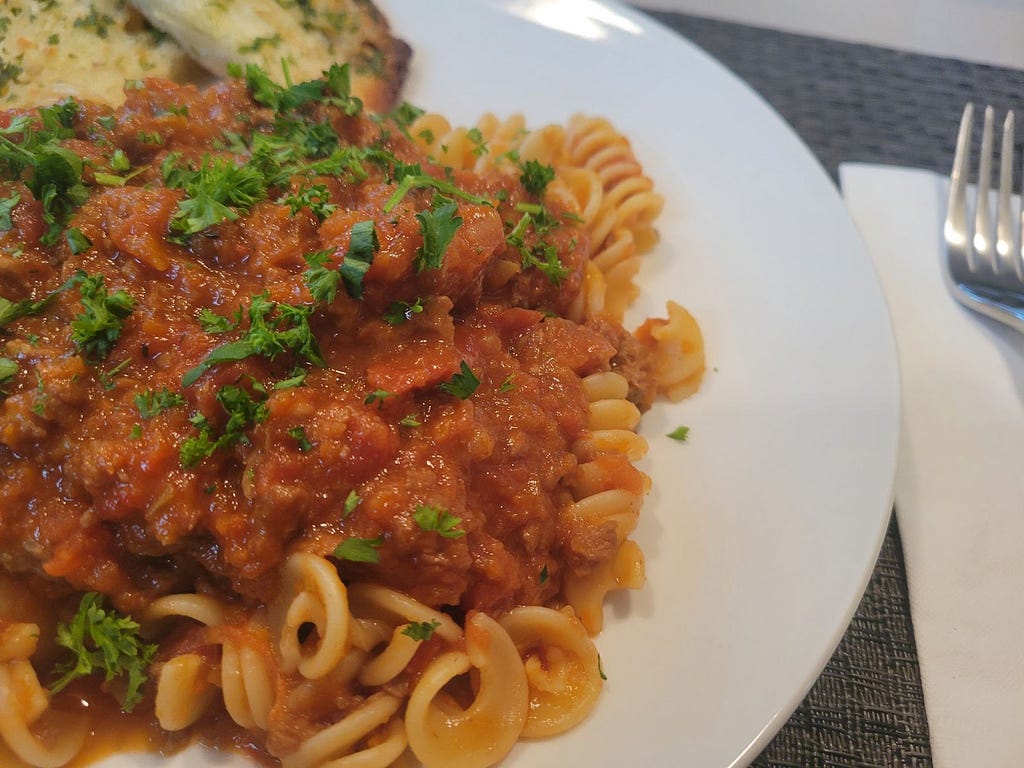 Succulently sauced spaghetti bolognese is pictured on a white plate.