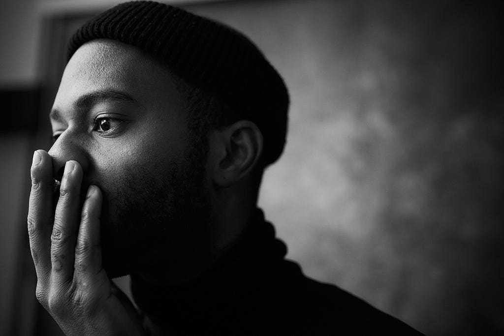 A black-bearded man wearing a beanie looking shocked or devastated