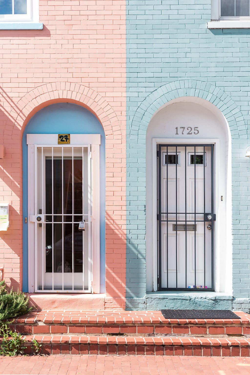 two almost identical front doors to two almost identical brick houses