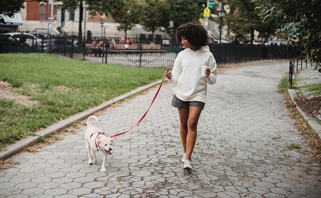 Image of a woman taking her dog for a walk outside