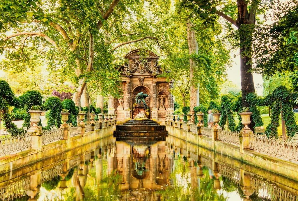 A fountain in a park surrounded by trees.