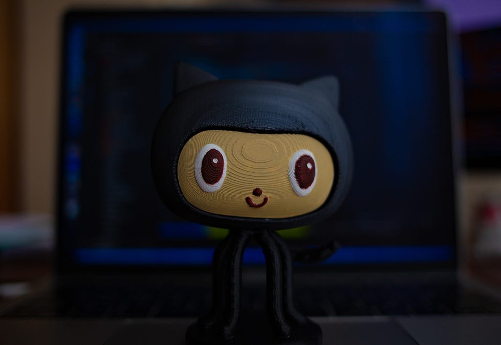 Github figurine positioned in front of a laptop