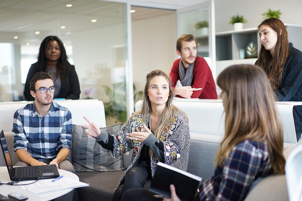 Group of 6 persons together for a meeting in a white room