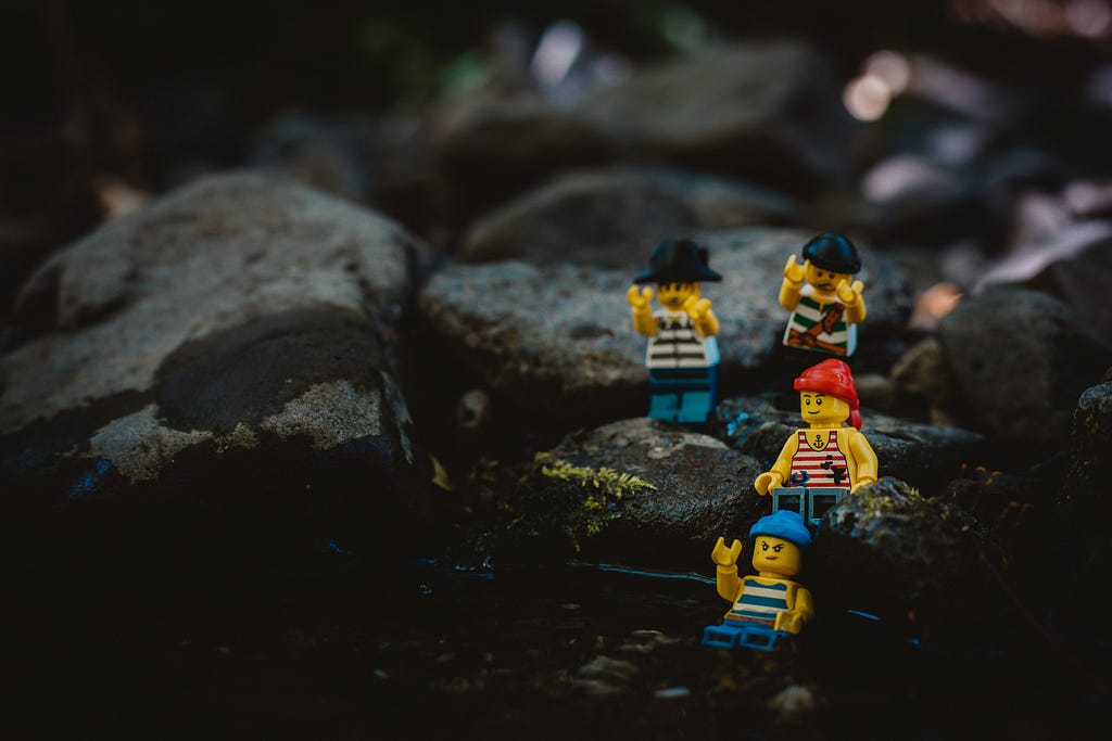A group of Lego pirates climb down a rocky sea shore.