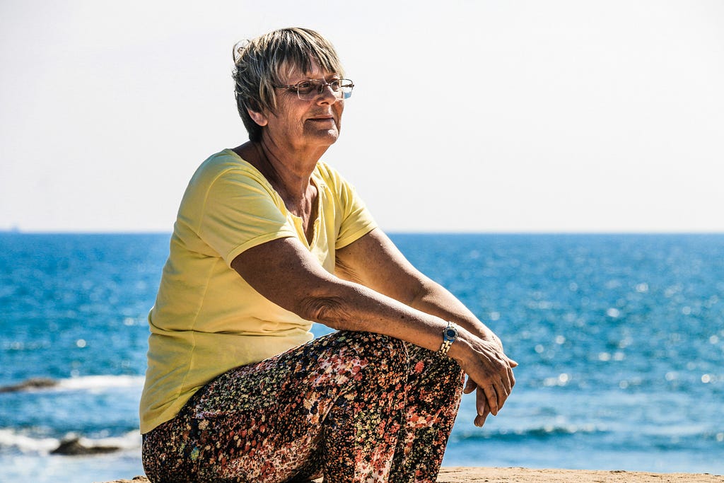 An old woman sitting on a beach