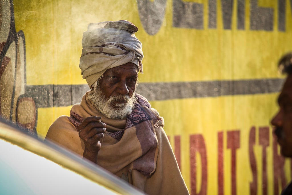 An old dark skinned man smoking a cigarette