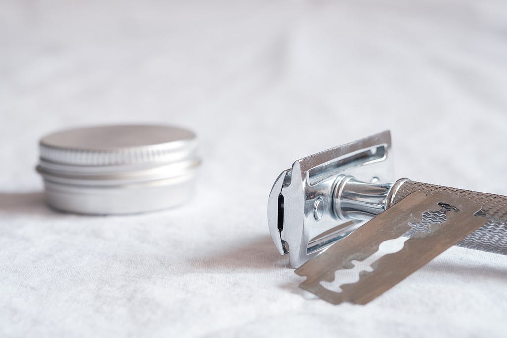 Silver safety razor with safety blade and enclosed circular, metal shaving soap tin.