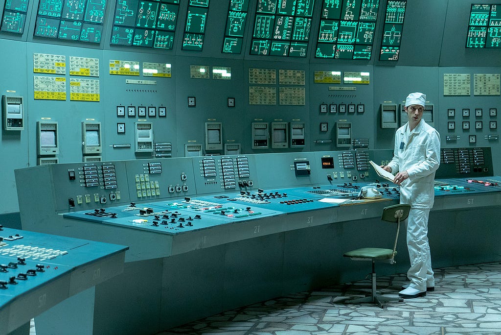 Man in white uniform standing in front of dated control panel