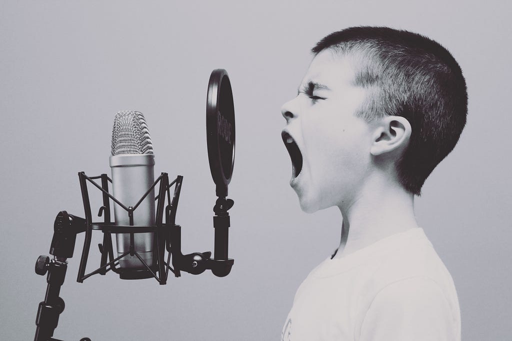 black and white image of young boy shouting into microphone