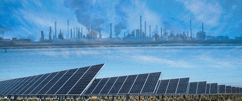 In the background, a line of smokestacks and plumes of smoke. In front: a field of solar panels.