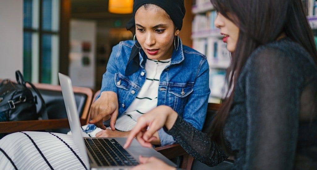 Two women talking and looking at a laptop