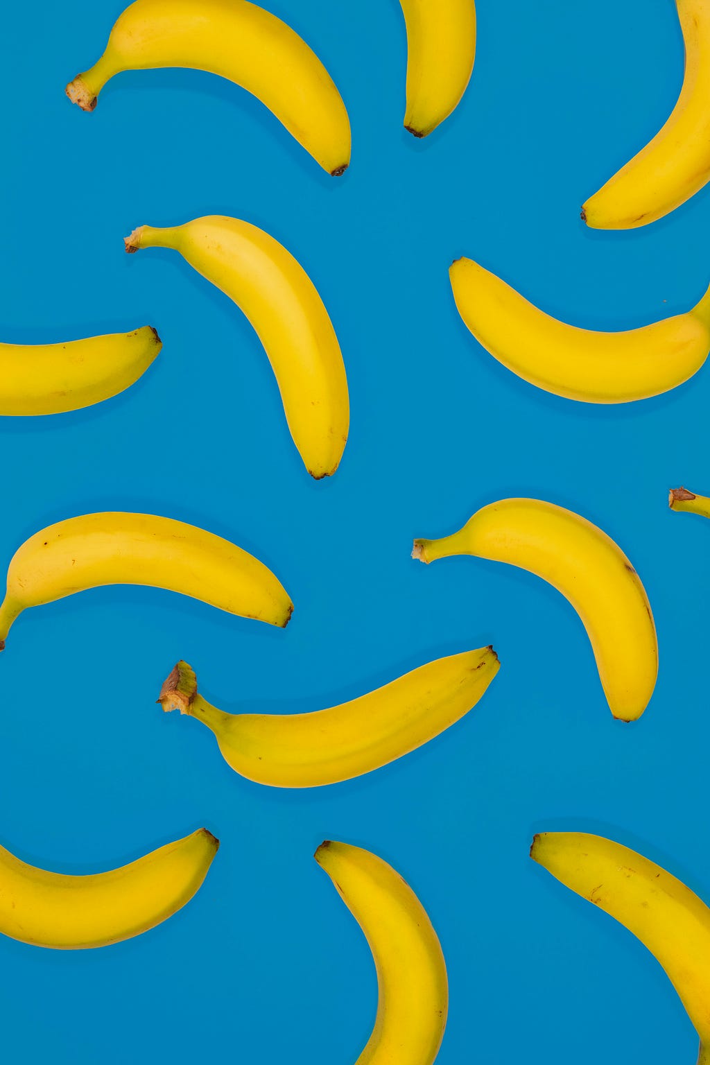 Blue background with many bananas spread around. It looks like they are falling from the sky.