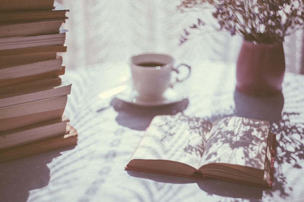 Opened book and coffee cup on table